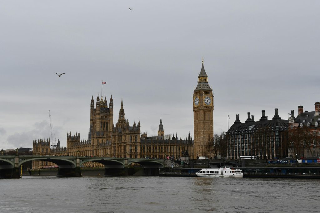 Towering Big Ben and Westminster Bridge over River Thames in London, UK.